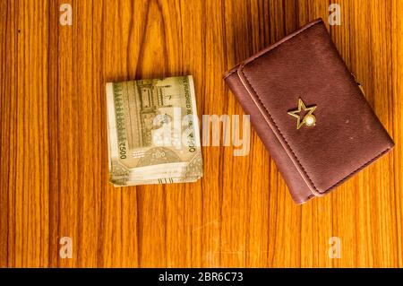 Indian cinquecento (500) rupee contanti nota di colore marrone portafoglio portafoglio in pelle su di un tavolo di legno. Finanza aziendale il concetto di economia. Alta Vista angelo wit Foto Stock