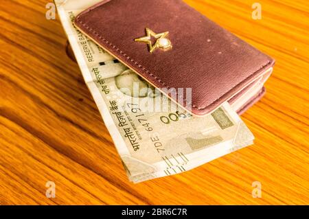 Indian cinquecento (500) rupee contanti nota di colore marrone portafoglio portafoglio in pelle su di un tavolo di legno. Finanza aziendale il concetto di economia. Lato Vista angelo wit Foto Stock