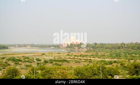 Banca del sud del fiume Yamuna e distante Taj Mahal nella luce della sera. La corona di palazzi, gioiello dell'arte musulmana", il marmo bianco mausoleo di emper Mughal Foto Stock