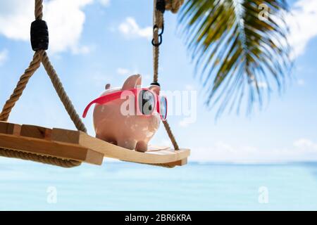 Close-up di Rosa Piggybank con gli occhiali da sole sul brandeggio in legno a Beach Foto Stock