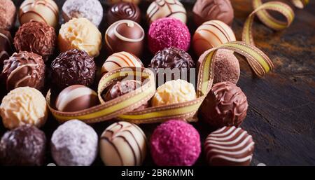 Assortimento di gourmet specialità artigianali praline di cioccolato con twirled festoso nastro per una celebrazione o dono nel panorama formato banner Foto Stock