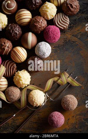 Varietà di deliziosi fatti a mano le sfere di cioccolato o praline visualizzati in un piatto ancora laici vita su legno rustico con un filo la forcella di sollevamento e con t Foto Stock