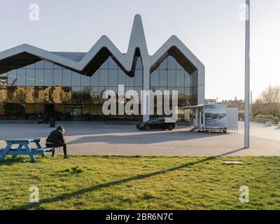 Un uomo seduto su una panchina vicino al Riverside Museum di Glasgow, socialmente distante e trascorrendo del tempo all'aperto durante la pandemia e il blocco globale del Covid 19. Foto Stock