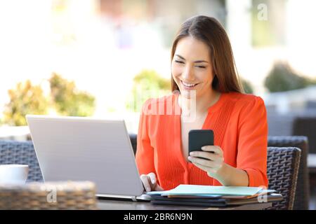 Felice imprenditore utilizzando più dispositivi elettronici seduta in una caffetteria e terrazza Foto Stock