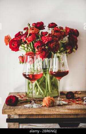 Sfumature di vino rosa. Vino rosato di diversi colori in bicchieri e fiori di fiori rossi di primavera su sfondo di tavola di legno. Enoteca, bar, degustazione vini Foto Stock