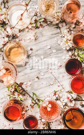 Varie sfumature di vino rosato. Piatto-lay di vino rosa di diversi colori in bicchieri e fiore primavera su sfondo bianco, vista dall'alto, copia spac Foto Stock