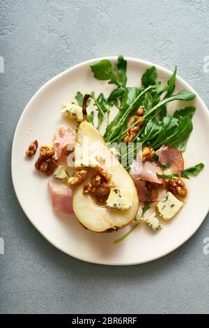 Insalata di pere con noci, prosciutto, rucola e formaggio blu. Antipasto per cena Foto Stock