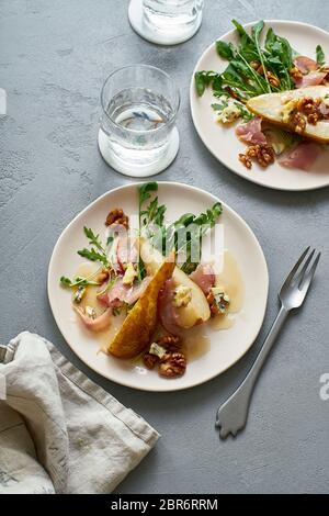 Insalata di pere con noci, prosciutto, rucola e formaggio blu. Antipasto per cena Foto Stock