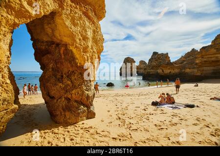 La gente si rilassa sulle spiagge di Lagos, Portogallo, dove spettacolari formazioni rocciose di arenaria si erigono dalle acque del Mar Mediterraneo Foto Stock