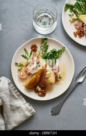 Insalata di pere con noci, prosciutto, rucola e formaggio blu. Antipasto per cena Foto Stock