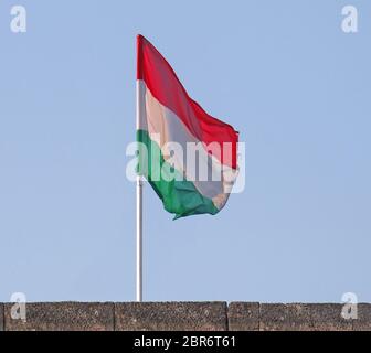 Nazionale bandiera ungherese al di fuori del vento contro il cielo blu Foto Stock