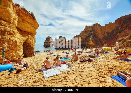 La gente si rilassa sulle spiagge di Lagos, Portogallo, dove spettacolari formazioni rocciose di arenaria si erigono dalle acque del Mar Mediterraneo Foto Stock