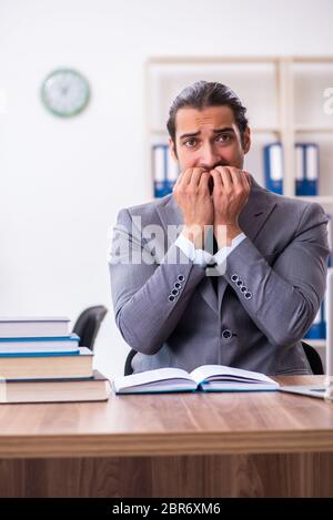 Giovane uomo d'affari che legge libri sul posto di lavoro Foto Stock