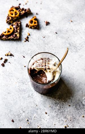 Budino di cioccolato in un bicchiere con panna montata al cocco e trucioli di cioccolato. Foto Stock