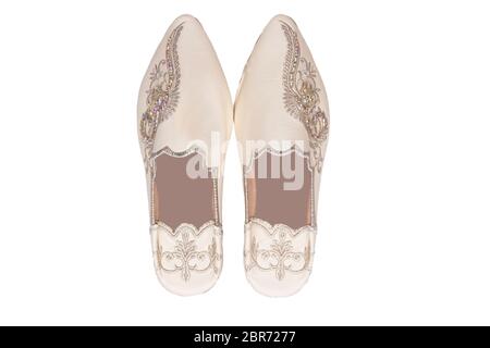 Pantofole donna isolato. Guardaroba di eleganti e lussuosi pantofole beige fatte a mano con splendidi ricami floreali e strass. Alla moda Foto Stock