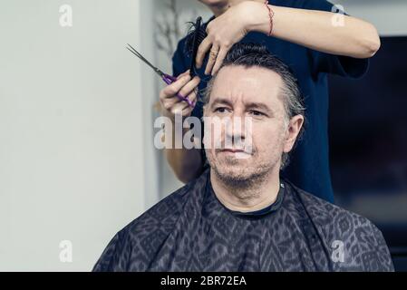 La moglie taglia i capelli sul marito a casa durante la quarantena in mezzo COVID-19 coronavirus pandemia Foto Stock