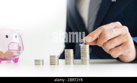 Close up di imprenditore moneta messa in piccoli salvadanaio , il concetto del risparmio e degli investimenti Foto Stock