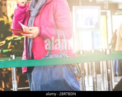 Irriconoscibile donna con una camicia rosa appena trattiene il passaporto in mano per i controlli di sicurezza prima di salire a bordo di un aereo Foto Stock