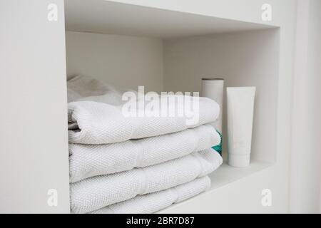 Asciugamani bianchi con sapone liquido nella cavità nella parete in bagno moderno Foto Stock