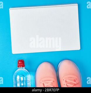Aprire il notebook vuota e sport abbigliamento femminile per lo sport e il fitness, vista dall'alto, sfondo blu Foto Stock