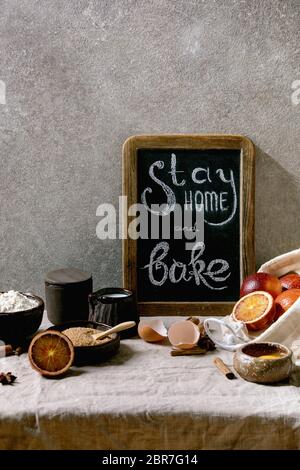 Ingredienti per la cottura. Concetto di periodo di isolamento della quarantena di soggiorno a casa. Lavagna vintage con scritta a mano in gesso, rimani a casa e cuoci al forno. Te grigio Foto Stock
