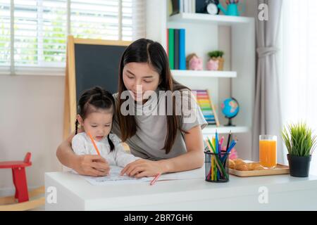 Ragazza studentesca asiatica con pittura madre immagine nel libro con matita a colori a casa, Homeschooling e l'apprendimento a distanza. Foto Stock