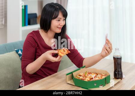 Donna asiatica virtuale happy hour incontro cena e mangiare cibo pizza online insieme al suo ragazzo in videoconferenza con tablet digitale per uno o Foto Stock