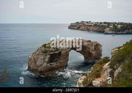 Es Pontas a Maiorca con barca ancorata nelle vicinanze del Mediterraneo. Maiorca Alba con yacht e arco di roccia vicino Santanyi. Maiorca Cala Llombar Foto Stock
