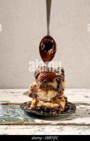 Trend Baking Brookies cioccolato brownies e biscotti torta fatta in casa tagliata da quadrati in pila in piastra di ceramica con salsa di cioccolato versante dal cucchiaio Foto Stock