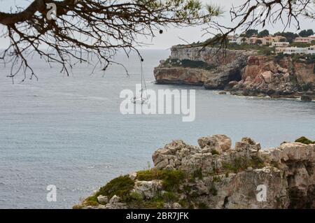 Es Pontas a Maiorca con barca ancorata nelle vicinanze del Mediterraneo. Maiorca Alba con yacht e arco di roccia vicino Santanyi. Maiorca Cala Llombar Foto Stock