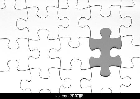 Grigio pezzo di puzzle in tra di bianco i pezzi del puzzle, la concezione di business Foto Stock