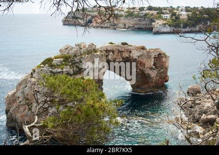 Es Pontas a Maiorca con barca ancorata nelle vicinanze del Mediterraneo. Maiorca Alba con yacht e arco di roccia vicino Santanyi. Maiorca Cala Llombar Foto Stock