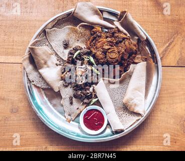 Injera cibo tradizionale e piatto nazionale di Etiopia ed Eritrea. Pasto consistente di injera e diversi tipi di wat o tsebhi (stufato) o (maraq), ty Foto Stock