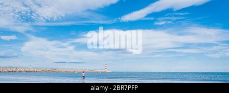 Faro di Port-la-Nouvelle in rosso e bianco su cielo nuvoloso in Occitanie, Francia Foto Stock