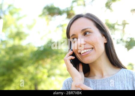 Donna felice colloqui su smart phone in piedi all'aperto in un parco Foto Stock