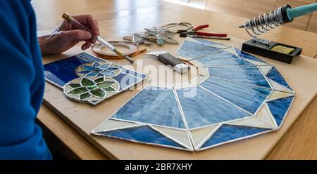 Donna che lavora su pannelli di vetro colorato hobby Craft con utensili, Scozia, Regno Unito Foto Stock