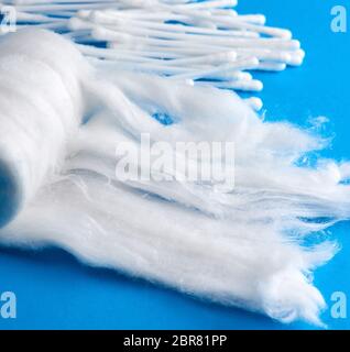 Rotolo di bianco cotone medicale e orecchio bastoni su uno sfondo blu, close up Foto Stock
