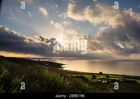 La Alcaidesa urbanizzazione, Cadice in Spagna sunrise con un orizzonte nuvoloso e il mare mediterraneo Foto Stock