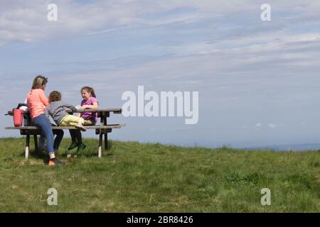 Piemonte, Italia - maggio 2020: Una famiglia seduta su una panchina in montagna ha dei picnic Foto Stock