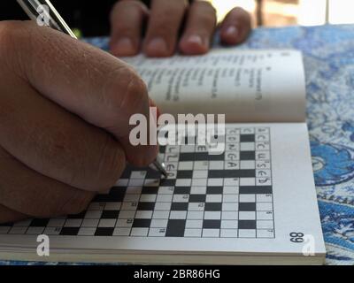 Uomo che completa un puzzle crossword Foto Stock