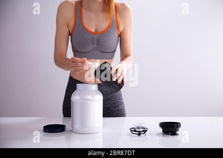 Giovane donna sportiva Preparazione Protein Shake prima di allenamento sulla scrivania Foto Stock