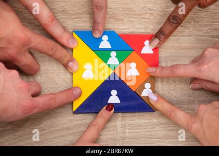 Angolo di Alta Vista del gruppo di persone la mano sulla colorata Tangram blocchi puzzle Foto Stock