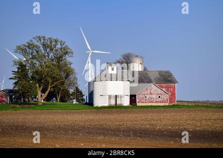 Shabbona, Illinois, Stati Uniti. Turbine eoliche si profilano su fienili e una fattoria in una fattoria nel nord-est dell'Illinois. Foto Stock