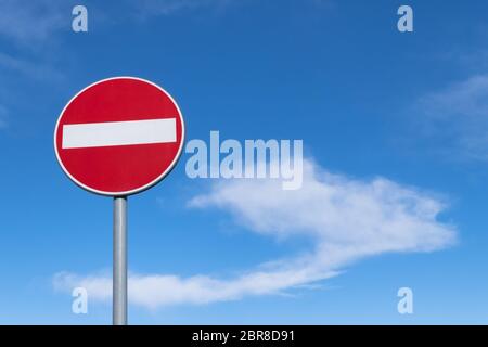 Segno di traffico il divieto di viaggiare in questa direzione, isolato su un cielo blu con sfondo nuvola bianca. Foto Stock