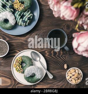Vegan ciambelle con semi di Chia e rabboccato con sani spirulina smalto con pistacchio,noce di cocco essicata e mirtillo.blu verde spirulina ciambelle, herba Foto Stock