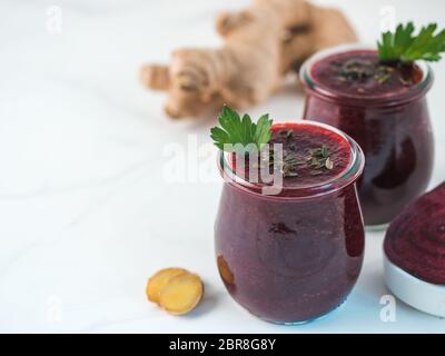 La barbabietola rossa fresca e radice di zenzero frullato. Frullato di barbabietole in un barattolo di vetro sul tavolo bianco. DOF poco profondo. Copia spazio per il testo. Pulire mangiare e detox conce Foto Stock