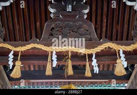 Uno shimenawa, la corda di paglia con strisce di carta bianca a zigzag (shide), che segna il luogo sacro sulle porte torii del santuario di Kitano Tenmangu. Kyoto. Giappone. Foto Stock