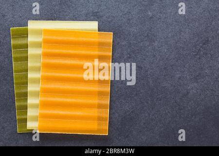 Materie tri color lasagne sfoglie di pasta, fotografato overhead su ardesia con copia spazio sul lato destro Foto Stock