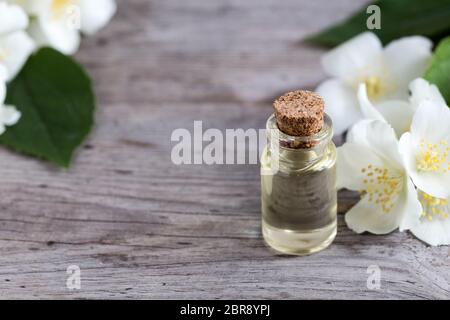 Essenziale gelsomino olio. Olio per massaggi con fiori di gelsomino su uno sfondo di legno. Foto Stock