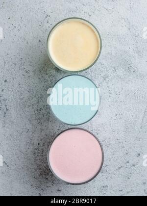 Bevande alla moda: Latte blu, giallo e rosa. Vista dall'alto del pisello a farfalla caldo o del latte di spirulina blu, del latte turmerico giallo o oro e del lat rosa di barbabietola Foto Stock